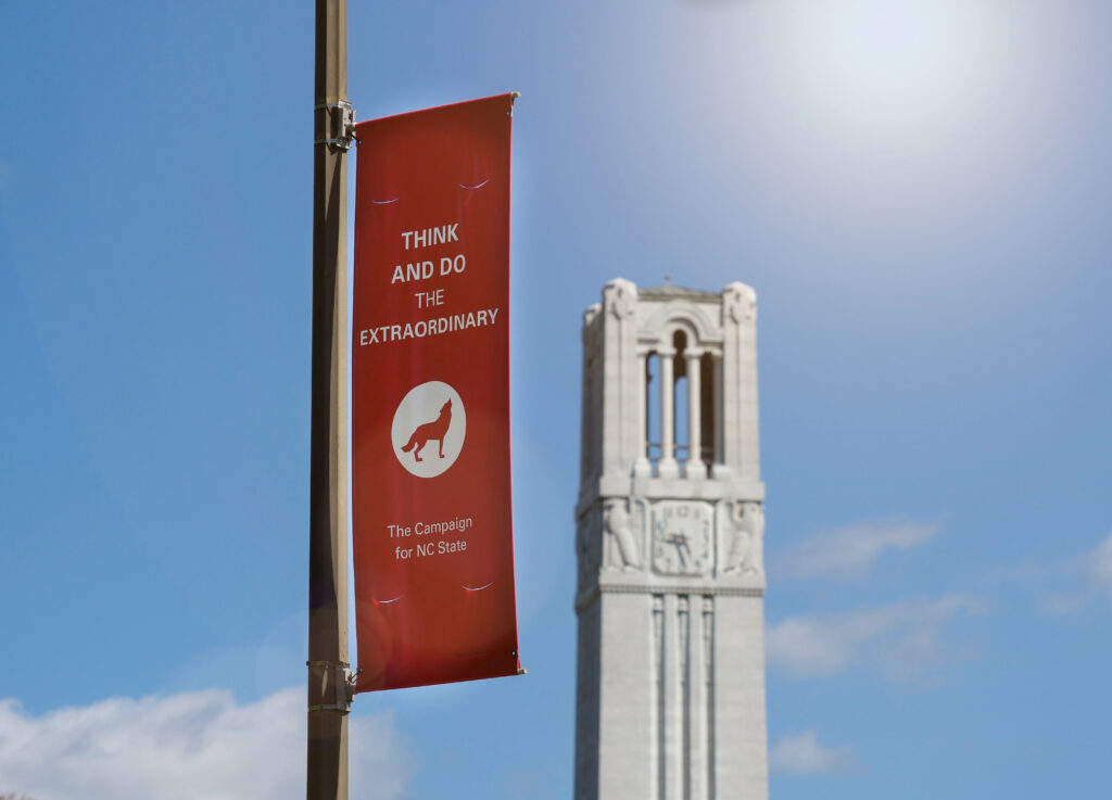 The NC State Belltower and a Think and Do the Extraordinary banner.