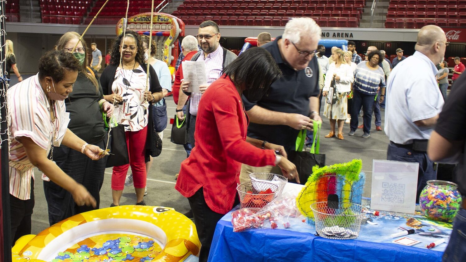 April Jones, Cristian Gradisteanu and Mardecia Bell interact with visitors at information table during the Staff and Faculty Appreciation Day in Reynolds Coliseum.