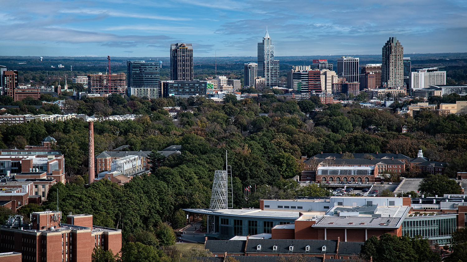 Aerial view of campus with city of Raleigh in the background.