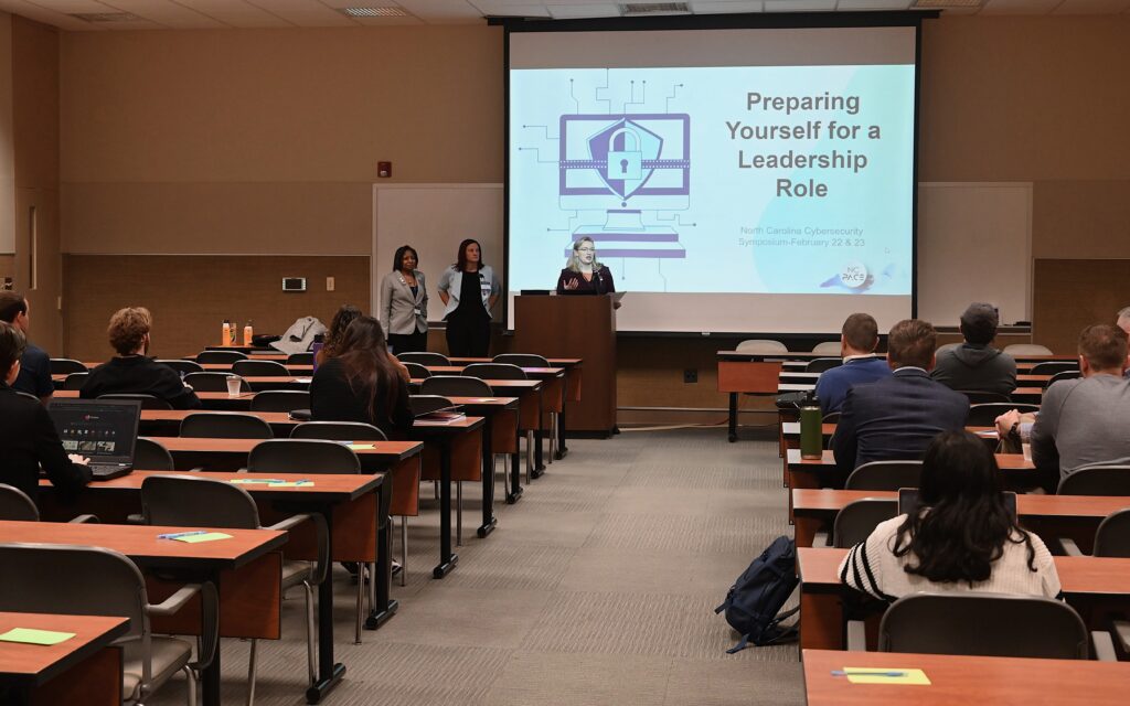 Mardecia Bell, left, presents at the North Carolina Partnership for Cybersecurity Excellence Cybersecurity Symposium with fellow Women in Technology member Donna Petherbridge, right.