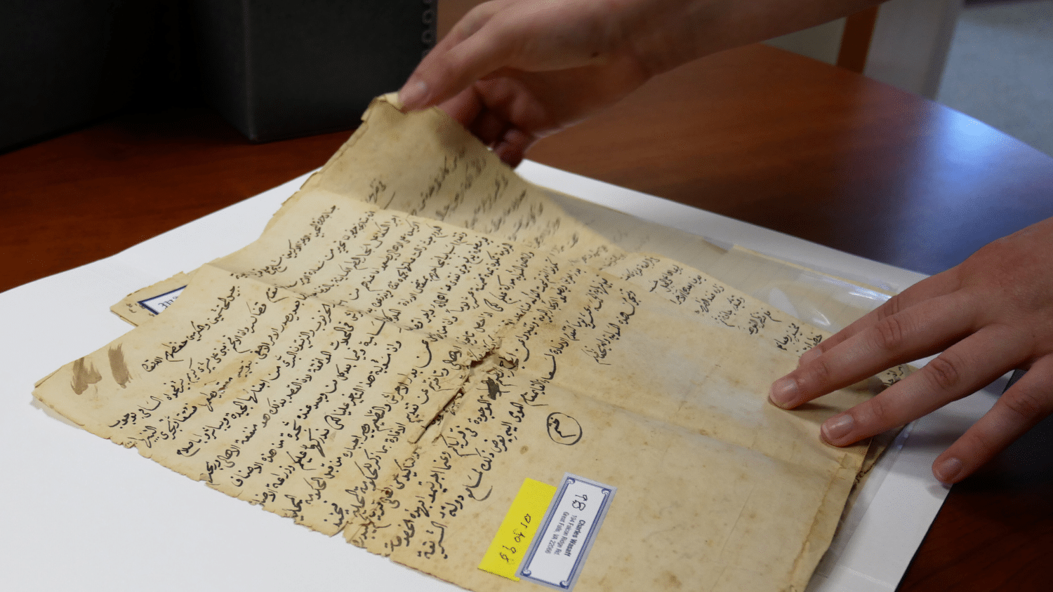 Hands hold an arabic manuscript
